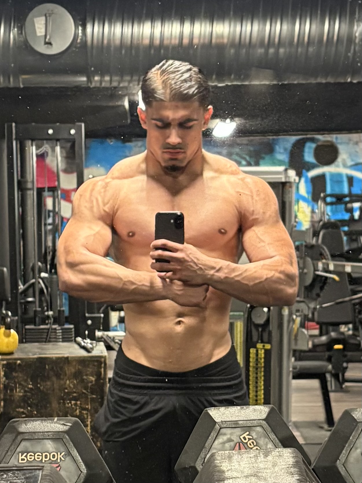 H1FIT coach showing competition-level physique in the gym